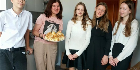 Powiększ grafikę: Pani Sylwia z talerzem pełnym sodkih wypieków w towarzystwie uczniów z klasy 8.