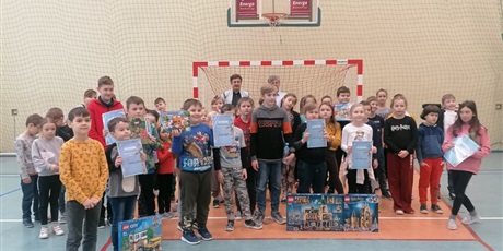 Powiększ grafikę: Uczniowie stoją z nagrodami na sali gimnastycznej